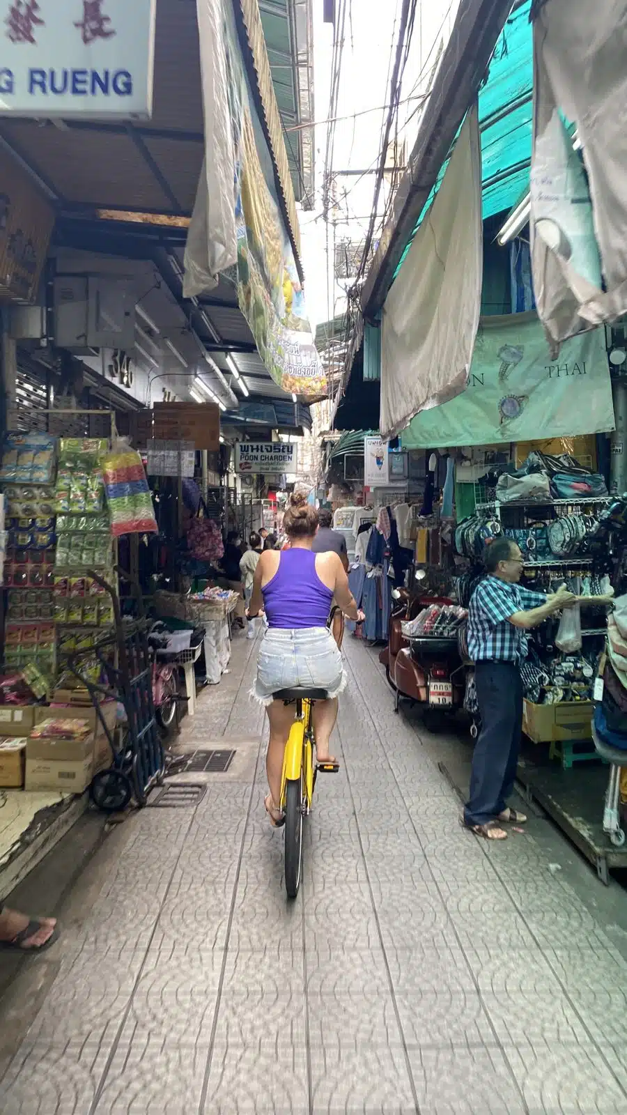Cycling through a covered market lane with small shops in Bangkok Chinatown