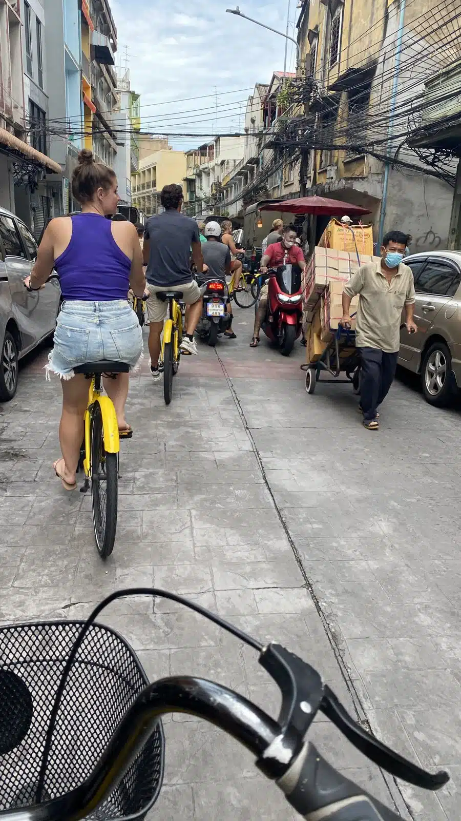 Cyclists and a street vendor in a side street of Bangkok Chinatown