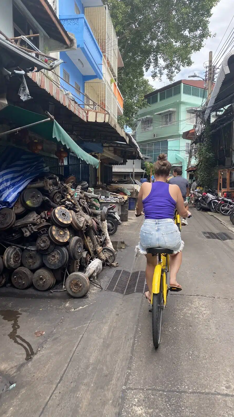 Riding past piles of old car parts in a lane in Talat Noi, Bangkok